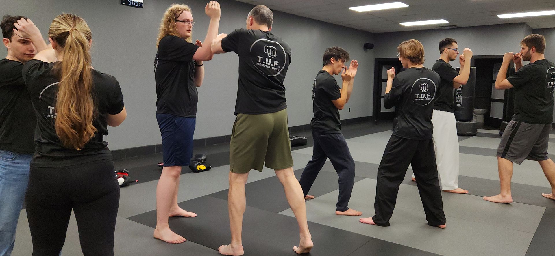 An adult self-defense class practicing strikes on the mat at T.U.F. Martial Arts